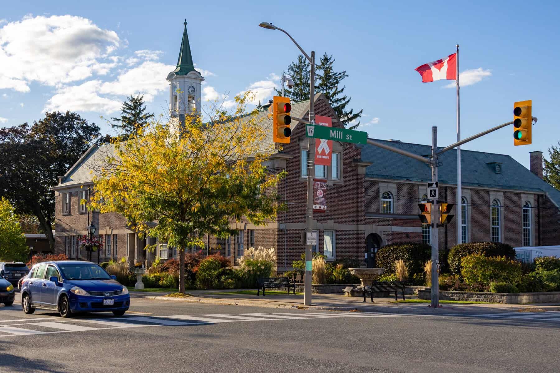 Newcastle Community Hall beside the Mill Street sign, with autumn trees and a Canadian flag